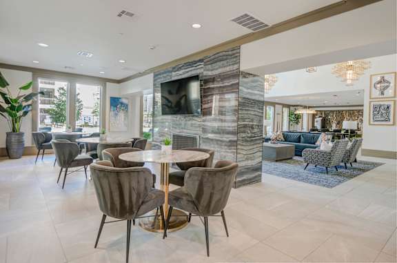 A modern dining room with a stone fireplace and grey chairs.