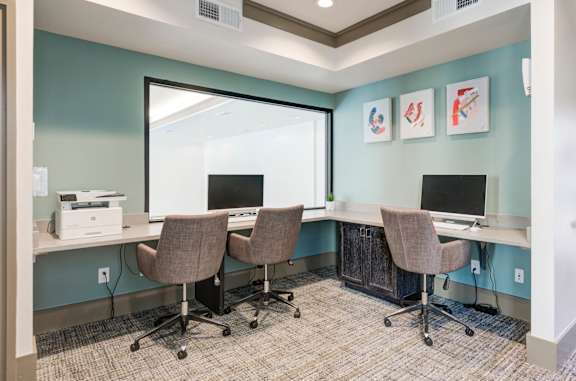 A room with a desk and chairs with a window in the background.