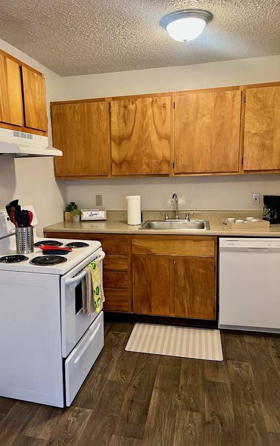 A kitchen with white appliances and wooden cabinets.