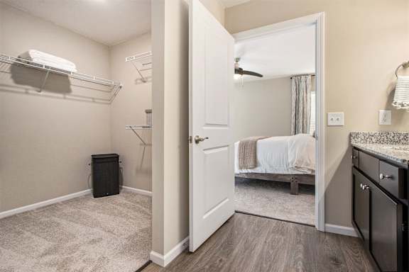 A small bedroom with a bed, a washing machine, and a trash can.