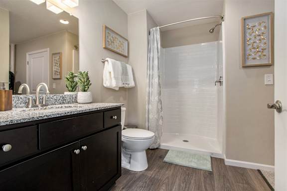 A bathroom with a white toilet, a sink with a marble countertop, and a shower with a glass door.