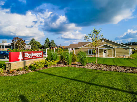 A sign for Redwood Apartment Homes is in front of a building.
