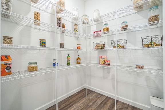 A white pantry with shelves stocked with food.