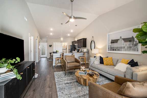 A living room with a couch, a coffee table, and a ceiling fan.