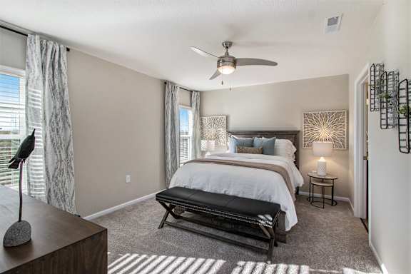 A bedroom with a large bed and a ceiling fan.