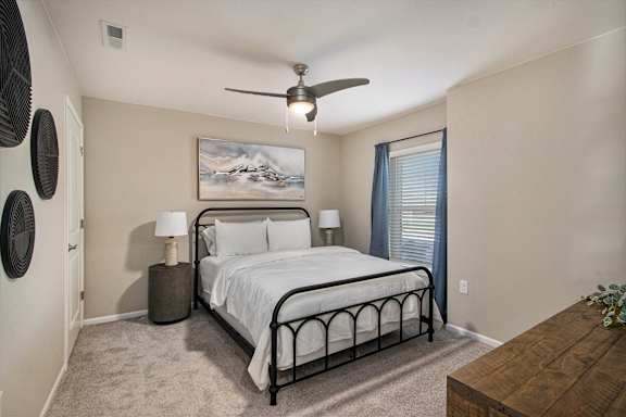 A bedroom with a bed, nightstand, and a painting on the wall.