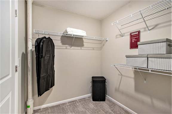 A small, empty closet with a black jacket hanging on a rod.