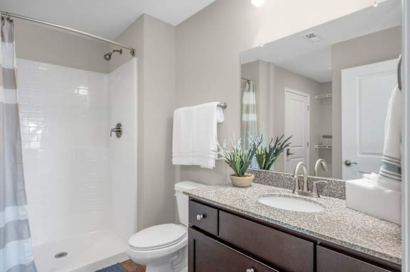 A bathroom with a toilet, sink, and shower.