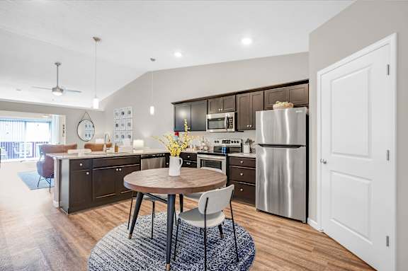 A modern kitchen with a round wooden table and a stainless steel refrigerator.