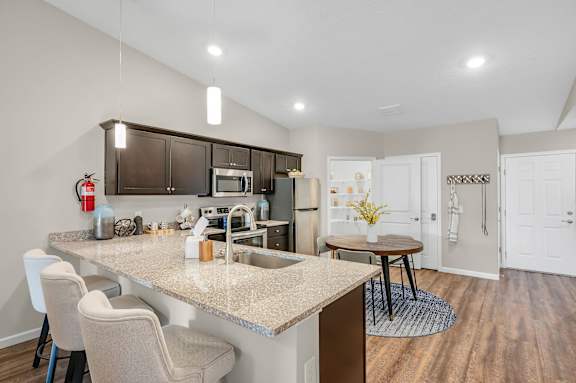 A kitchen with a table and chairs in front of a sink.
