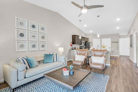 A living room with a white couch, a coffee table, and a ceiling fan.