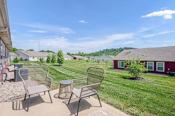 A patio with two chairs and a table is in front of a house.