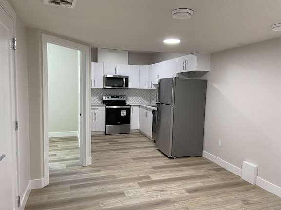 A kitchen with a refrigerator, microwave, and oven.