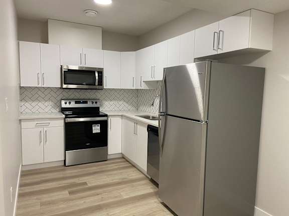 A kitchen with a stainless steel refrigerator, microwave, and oven.