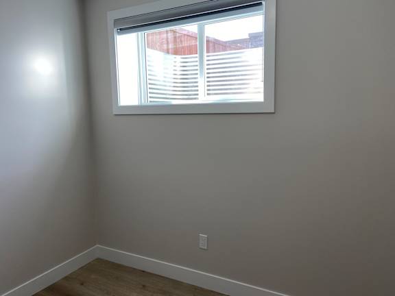 A room with a window and a light switch on the wall.