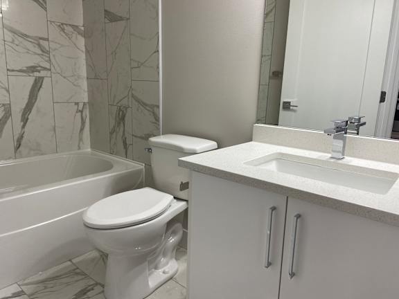 A white toilet sits next to a bathtub in a bathroom.