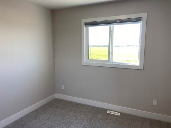 A room with a window and a grey carpet.