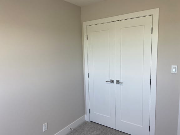 A white door with a silver handle is in a room with white walls.