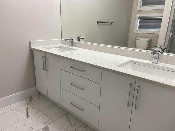 A bathroom with a white counter top and a mirror.