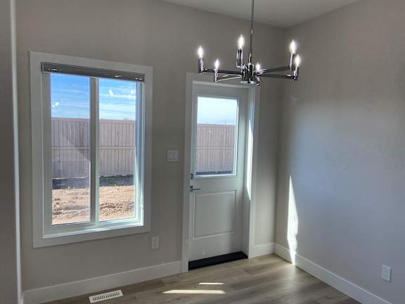 A room with a white door and a window with a view of a fence.