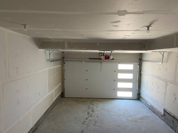 A room with a white ceiling, walls, and floor with a door and a fan.