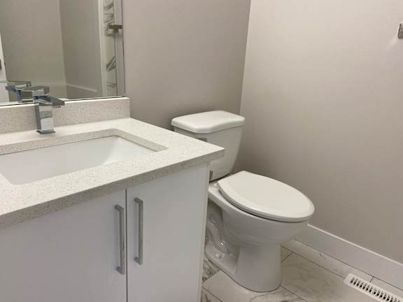A white toilet sits next to a sink in a bathroom.