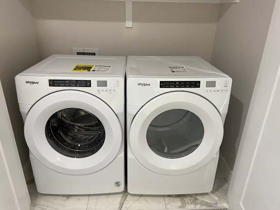 Two white washing machines in a small room.