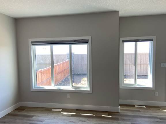 A room with two windows and a wooden fence outside.
