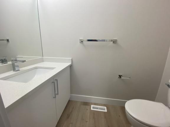 A white bathroom with a toilet, sink, and mirror.