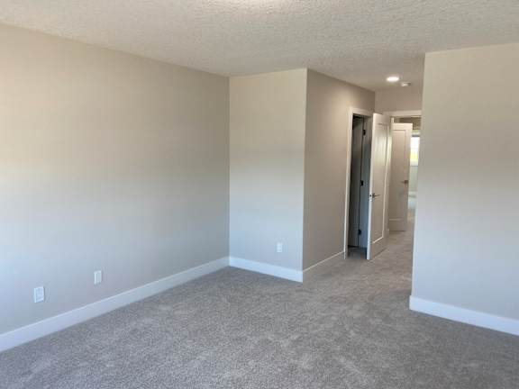 A room with a carpeted floor and a doorway leading to another room.