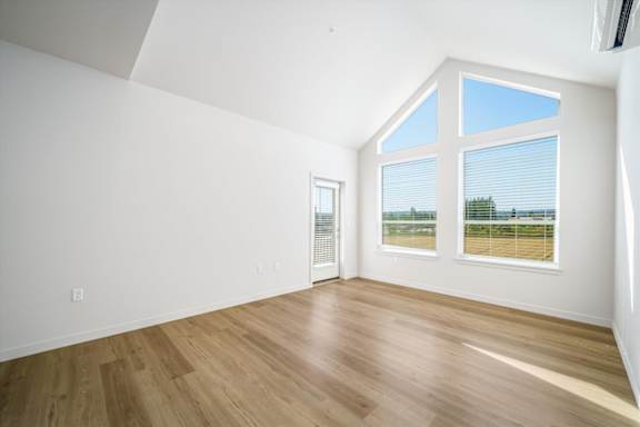 A room with a wooden floor and a large window with blinds.