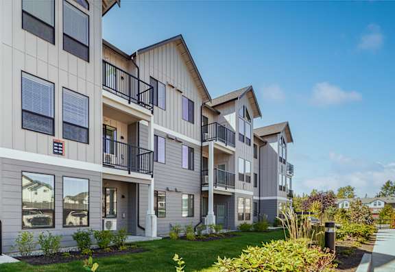 A row of modern townhouses with balconies and landscaped gardens.