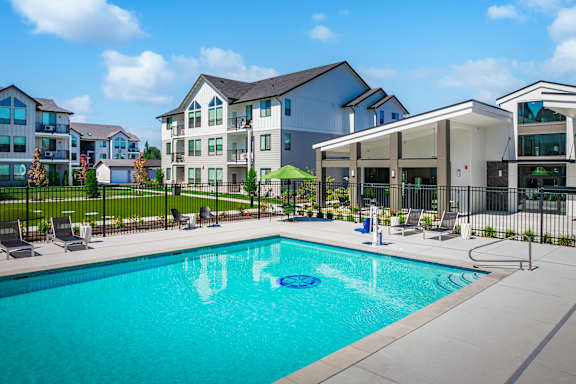 A swimming pool in front of a building with a black fence around it.