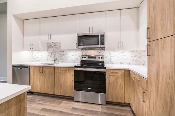 A modern kitchen with wooden cabinets and a marble backsplash. at Morea Apartments, Pompano Beach, 33062