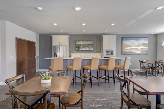 a community room with tables and chairs and a kitchen