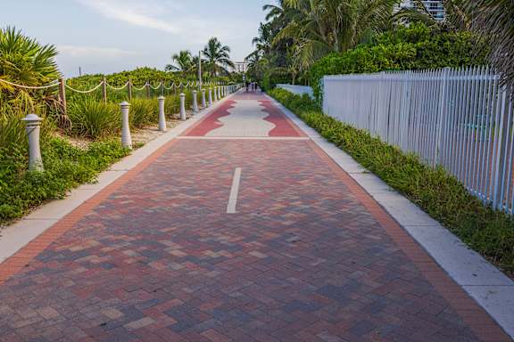A red brick pathway leads through a tropical setting.
