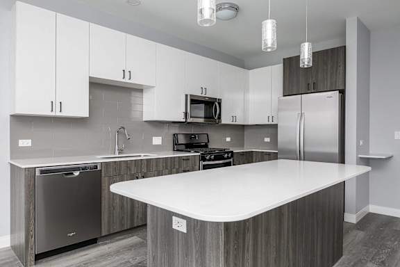 A modern kitchen with a white island and stainless steel appliances.