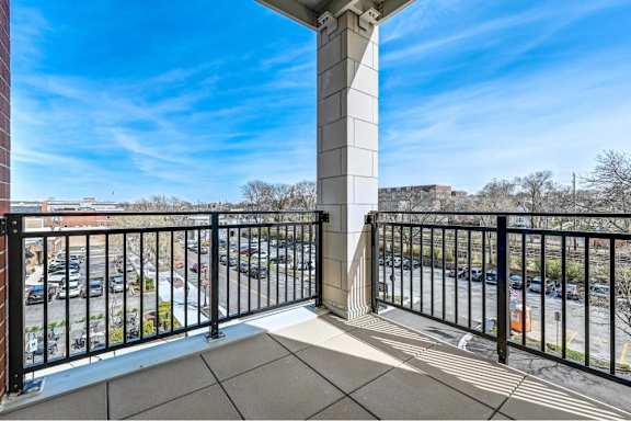 A balcony with a black railing and a white column.