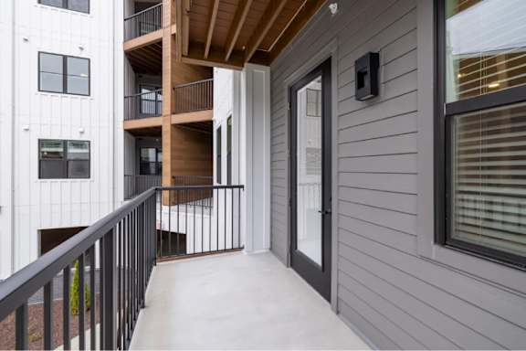 A balcony with a black railing and a wooden ceiling.