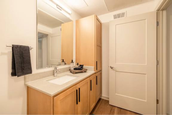 A bathroom with a sink, mirror, and wooden cabinets.