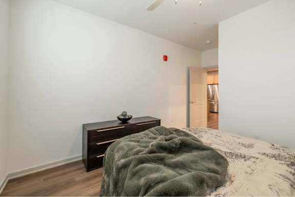 A bedroom with a bed, a nightstand, and a door.