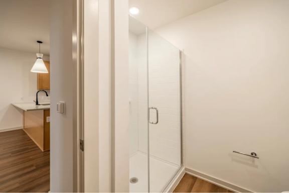 A white door with a handle and a glass panel is in a room with a wooden floor.