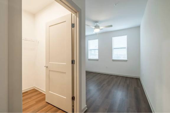 A room with a white door and a ceiling fan.