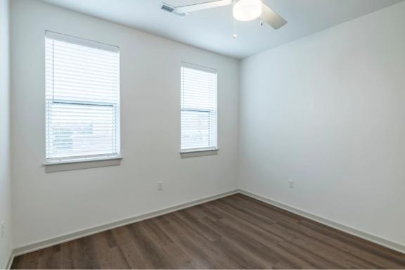 A room with wooden floors and two windows.