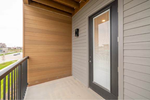 A balcony with a glass door and a black railing.