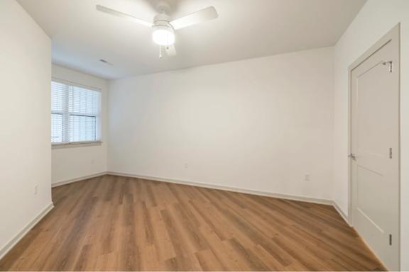 A room with wooden flooring and a ceiling fan.