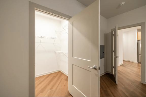 A white door is open to a room with wooden floors.