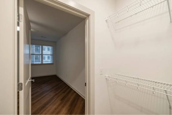 A white wire shelf in a white room with wood flooring.