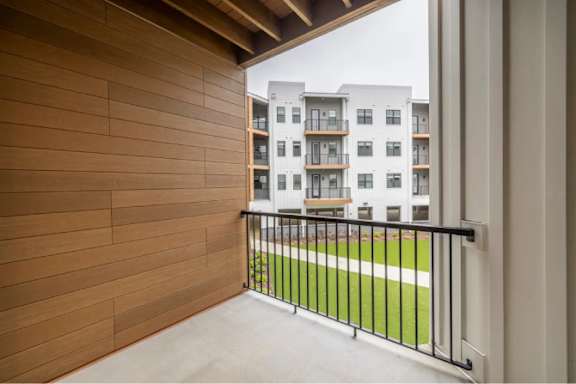 A balcony with a black railing and a wooden wall.