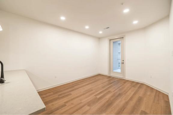 A room with wooden flooring and a white door.